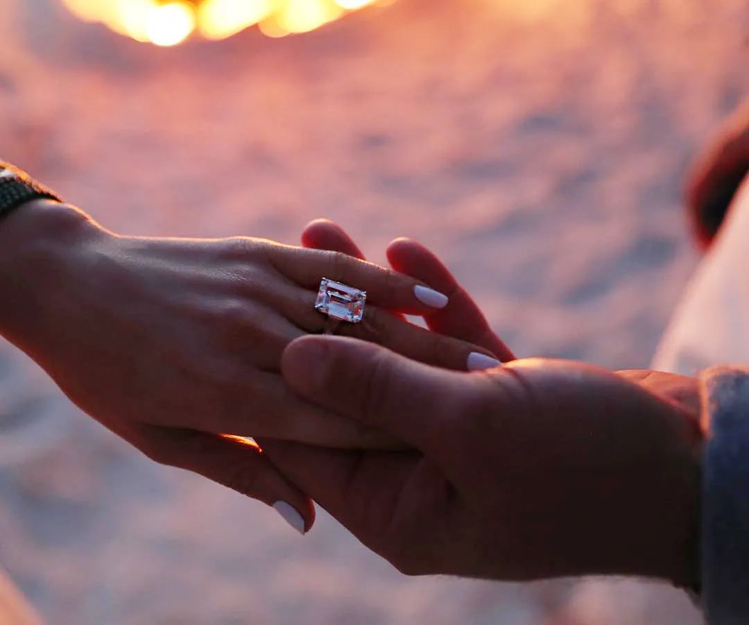 Close-up of hands with Jennifer Lopez's Iconic 16-Carat Emerald Diamond Ring during sunset